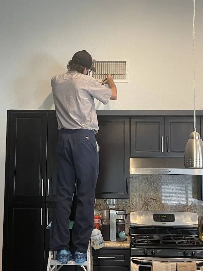 Technician inspecting an air vent during HVAC service in Cannon